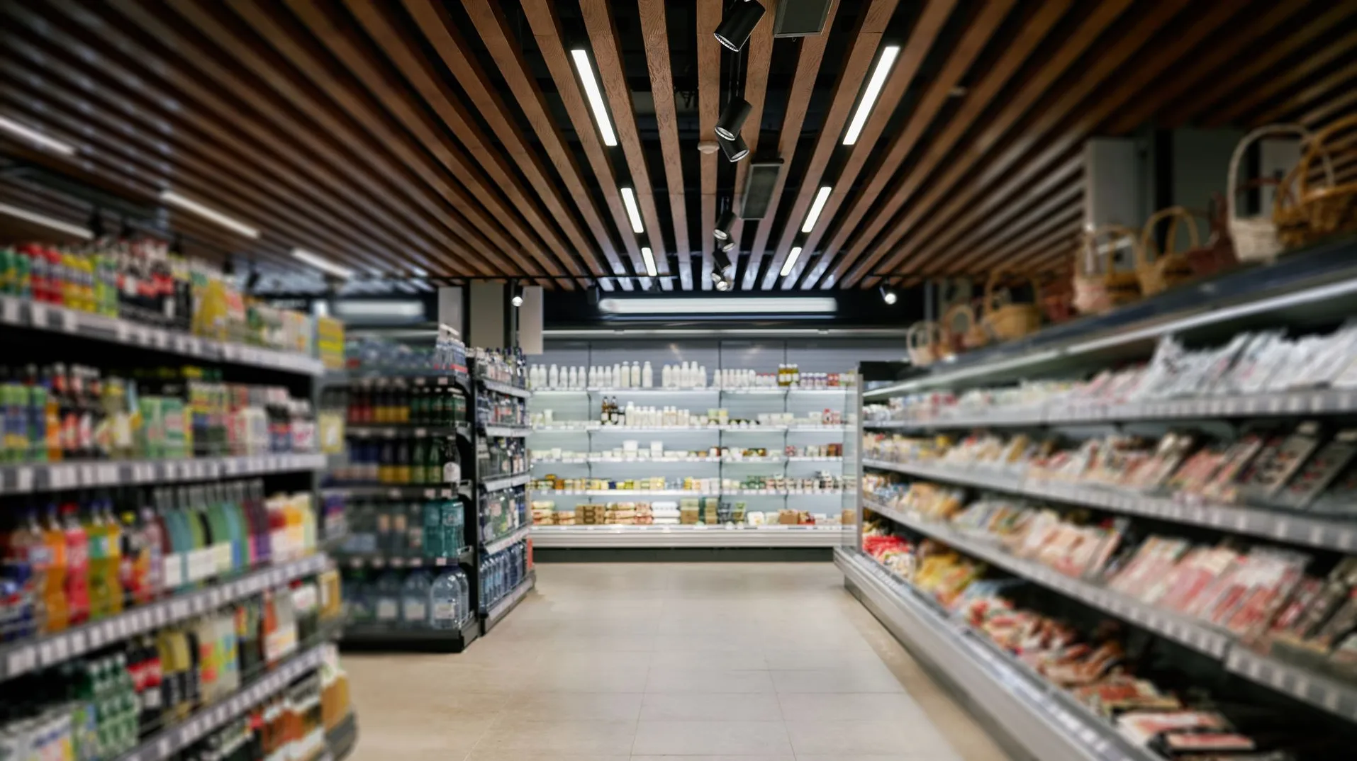 Unutrašnjost moderne prodavnice sa policama punim raznovrsne hrane i pića, te osvijetljenim plafonom sa drvenim detaljima.