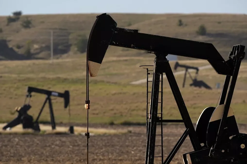 Crna pumpa za naftu u prvom planu s još dvije u pozadini na suhom polju pod vedrim nebom.