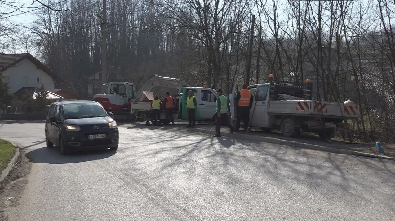 Radovi na cesti sa bagerom, radnim vozilima i radnicima u zaštitnim prslucima