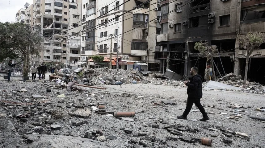 Jedan muškarac hodajući kroz urušenu ulicu punu šuta i ostataka eksplozije.