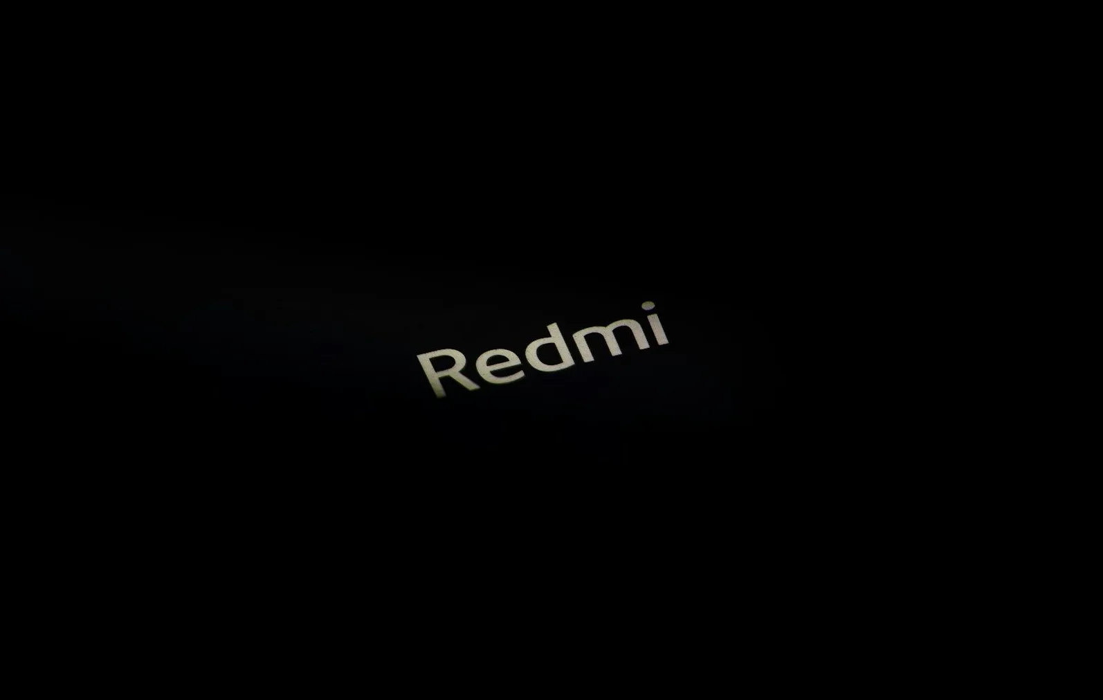 Srebrni natpis "Redmi" na crnoj pozadini.