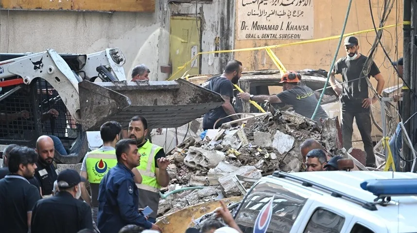 Radnici u zaštitnoj opremi uklanjaju ruševine nakon nesreće, koristeći građevinsku mašinu.