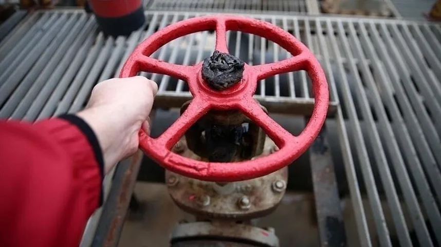 Ruka okreće crveni ventil na industrijskoj cijevi