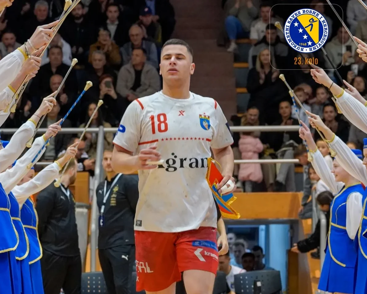 Rukometni igrač sa brojem 18 na dresu, koji prolazi kroz kordon navijača sa zastavom.