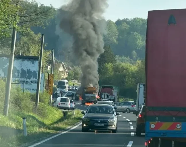 Saobraćajna nesreća sa zapaljenim kamionom na putu, gusti crni dim se diže u zrak.