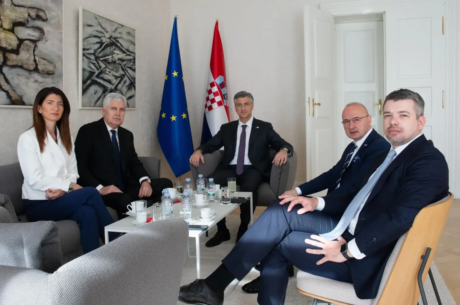 Petoro političara sjedi na sastanku, sa zastavama EU i Hrvatske u pozadini.