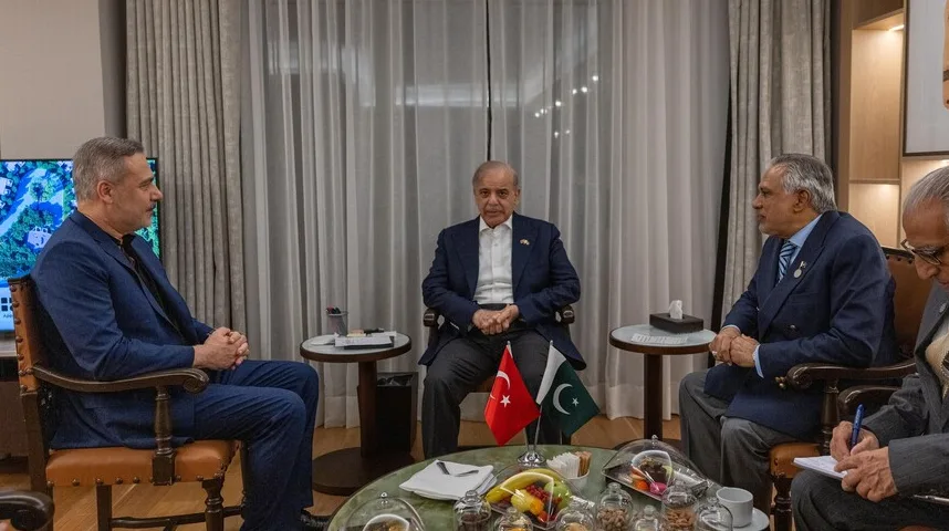 Tri muškarca sjede za okruglim stolom, a ispred njih se nalaze zastave Turske i Pakistana.