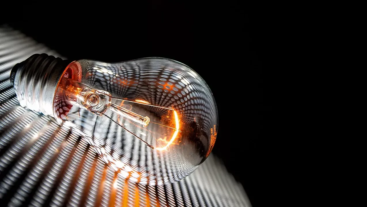 Blisko snimljena klasična sijalica sa užarenom niti koja leži na rebrastoj površini.