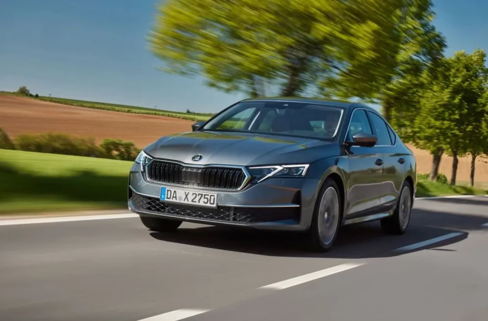 Siva Škoda Octavia vozi se seoskim putem pored zelenih polja.