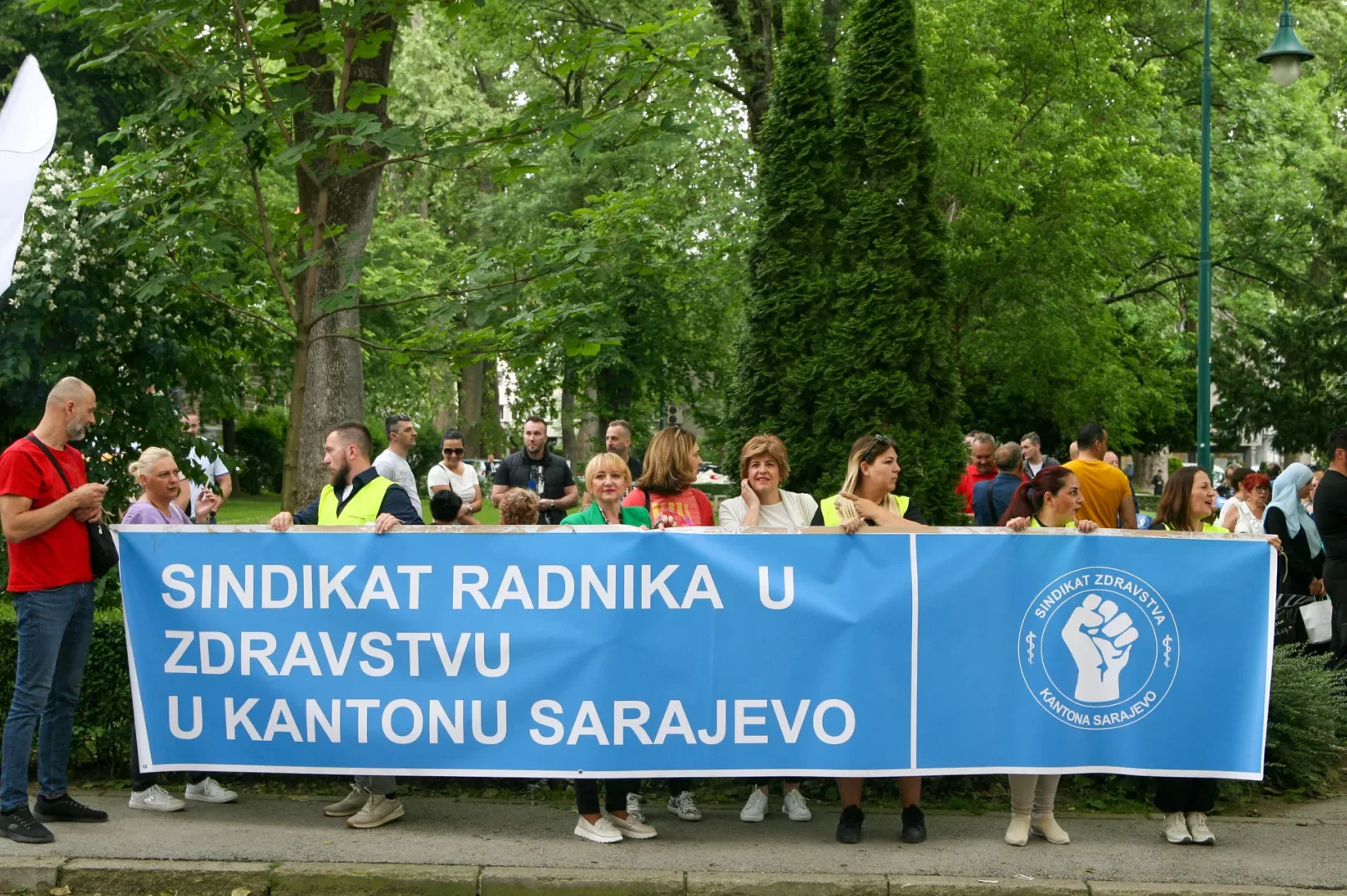 Članovi Sindikata zdravstva Kantona Sarajevo drže plavi transparent sa natpisom "Sindiakt radnika u zdravstvu u Kantonu Sarajevo" i logom sindikata.