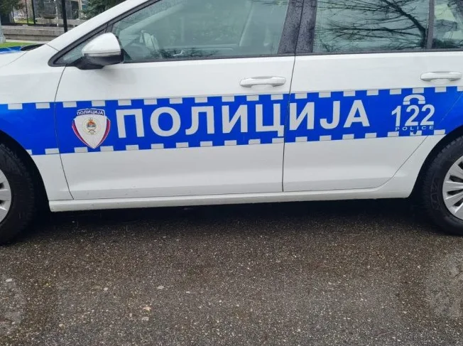 Bijelo policijsko vozilo sa plavom trakom i natpisom "POLICIJA 122 POLICE"
