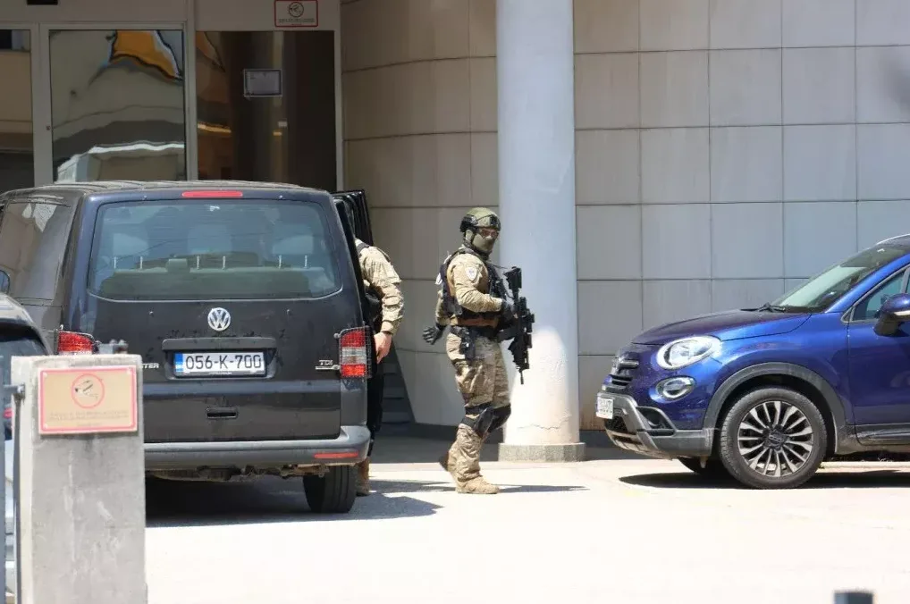 Specijalci u punoj opremi stoje pored crnog kombija i plavog automobila