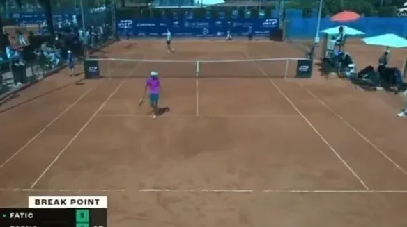 Teniski meč sa igračem u ljubičastoj majici na šljaci, u toku je 'Break Point'.