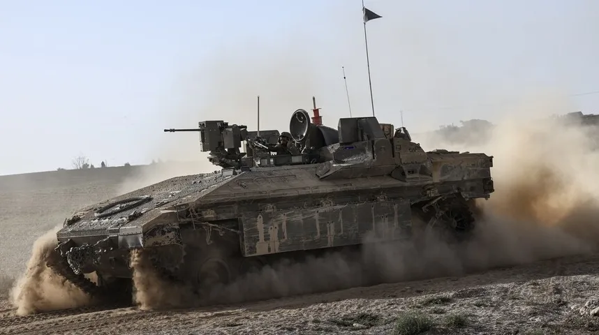 Borbeni tenk se kreće po pješčanom terenu, podižući oblake prašine.