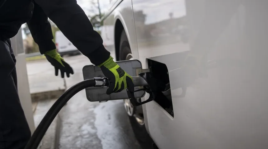 Osoba u rukavicama toči gorivo u bijeli kombi na benzinskoj pumpi.