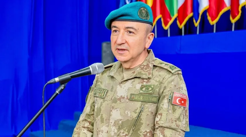 Turski general u uniformi sa oznakama 'TUR ARMY' i zastavom Turske, govori za govornicom.