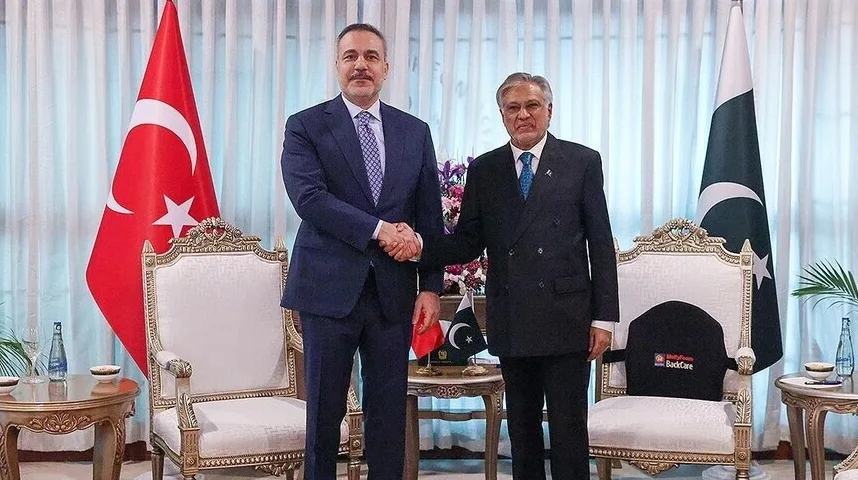 Dva gospodina u odijelima se rukuju pred turskom i pakistanskom zastavom.