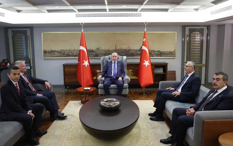 Turski predsjednik Recep Tayyip Erdoğan sjedi u fotelji okružen sa strane sa dvojicom muškaraca u odijelu, dok dvojica zvaničnika sjede na sofi naspram njega.