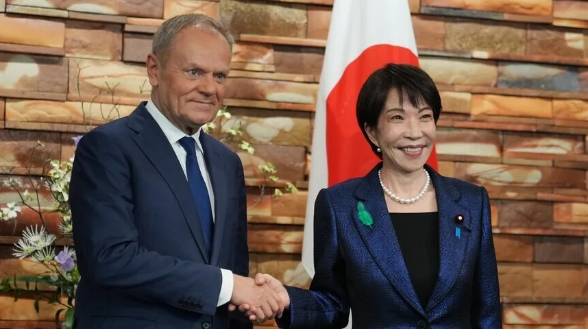 Donald Tusk i japanska zvaničnica se rukuju ispred zastave Japana