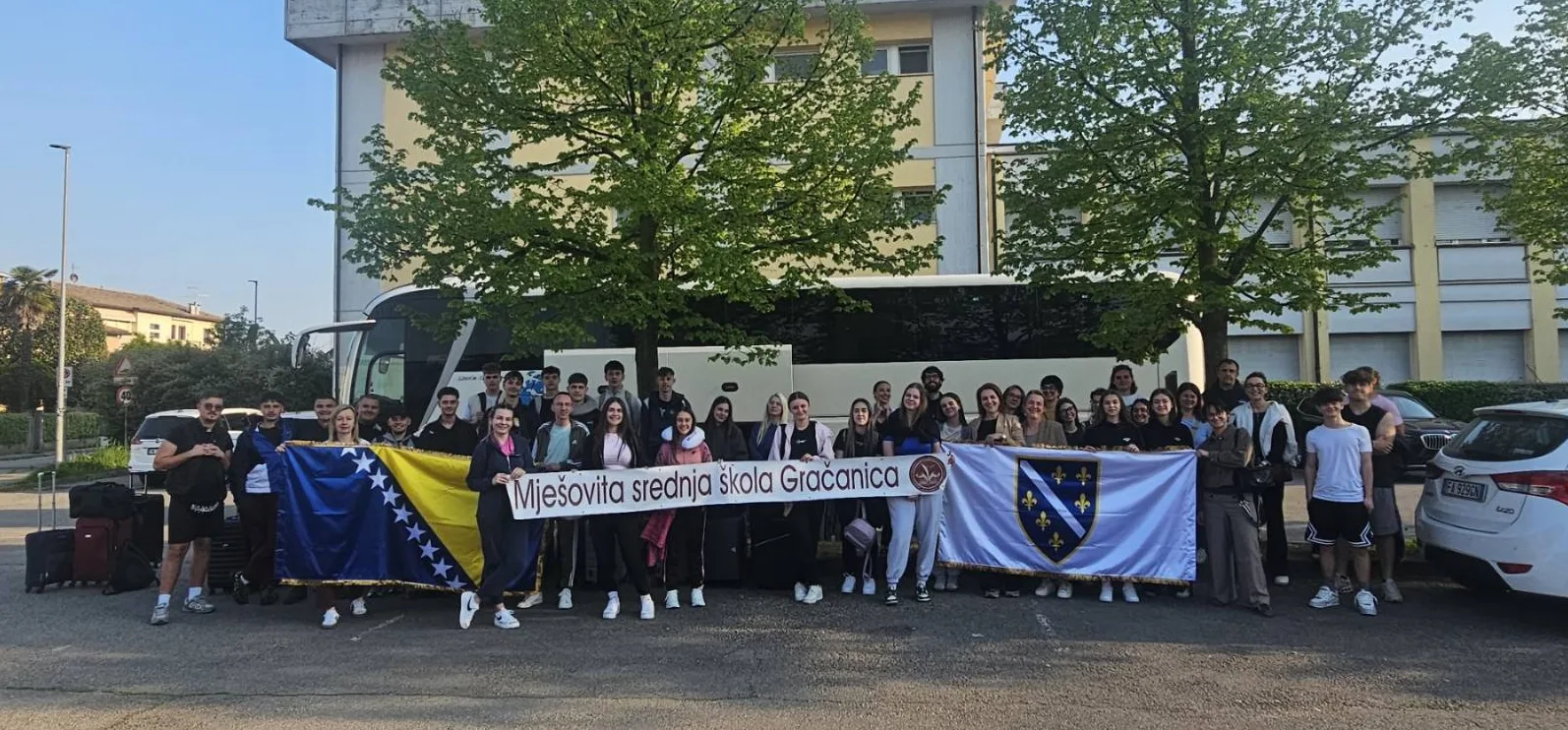 Učenici i profesori Mješovite srednje škole Gračanica drže zastave Bosne i Hercegovine i druge zastave sa grbom škole.