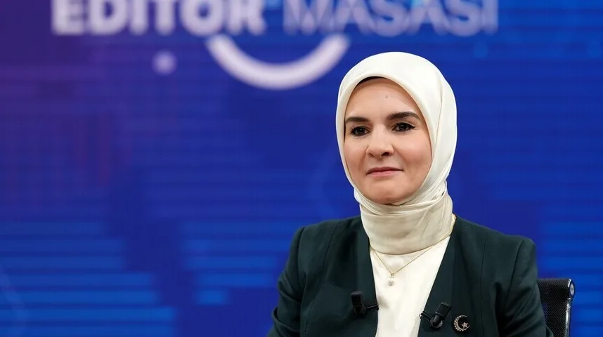 Žena u hidžabu i tamnom sakou sjedi ispred plave pozadine s natpisom "EDITOR MASASI".