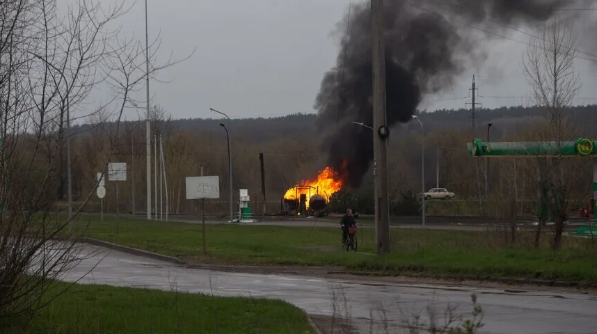 Benzinska pumpa u plamenu sa gustim crnim dimom koji se diže u nebo.