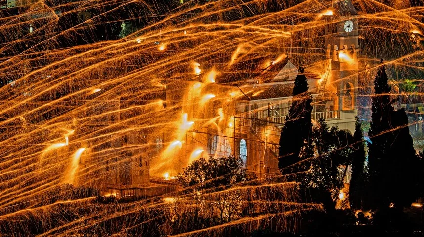 Vatreni tragovi od pirotehnike prelaze preko arhitektonskog objekta sa tornjem na kojem je sat, tokom noćne proslave.