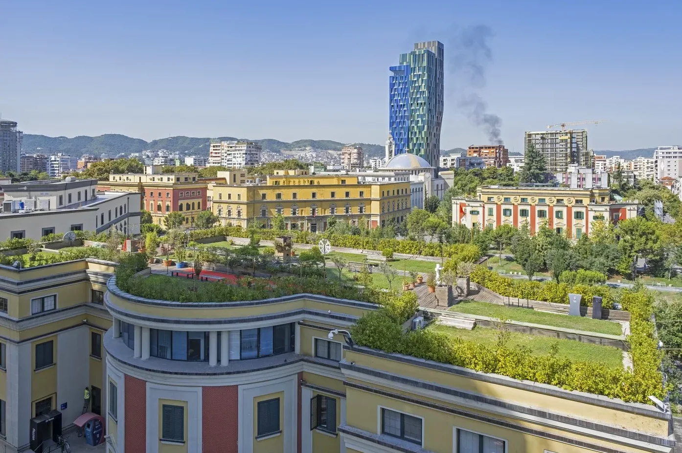 Panoramski pogled na zgradu vlade Albanije sa zelenim krovovima i moderni plavo-zeleni neboder u pozadini, u Tirani, Albanija.