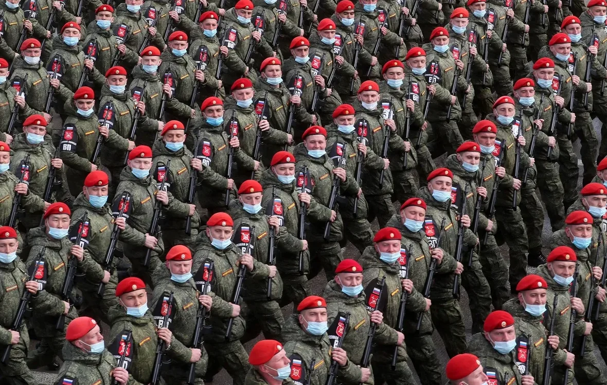 Veliki broj vojnika u zelenim uniformama i crvenim beretkama, nose oružje, na vojnoj paradi u Rusiji.