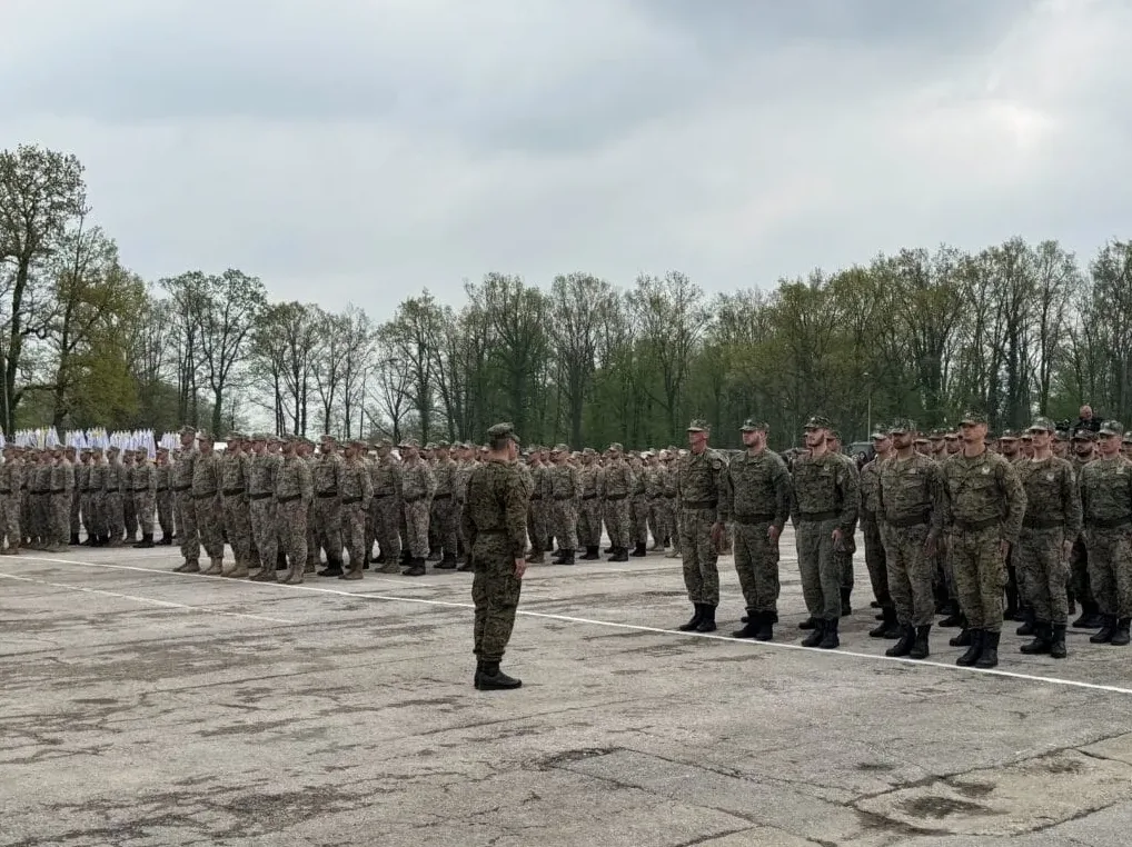 Vojnici u vojnim uniformama stoje u stroju na otvorenom, ispred njih stoji jedan vojnik okrenut leđima.