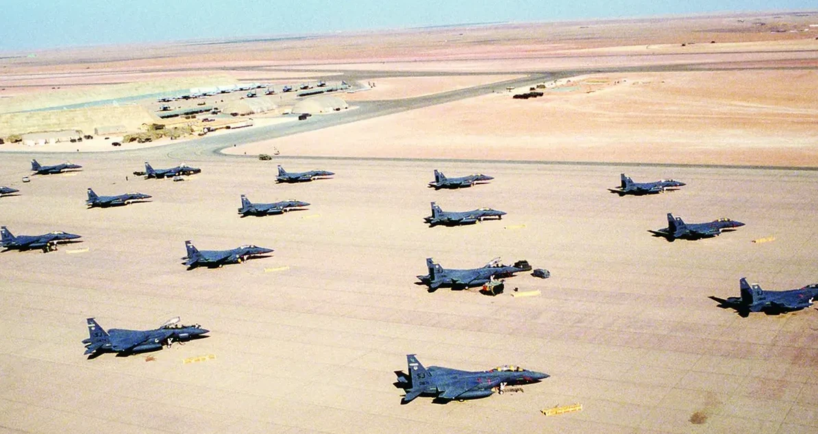 Veliki broj vojnih lovaca McDonnell Douglas F-15 Eagle parkiranih na pustinjskom aerodromu.