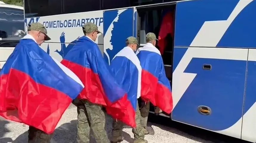 Grupa vojnika u uniformama ogrnuta ruskim zastavama ulazi u plavo-bijeli autobus.