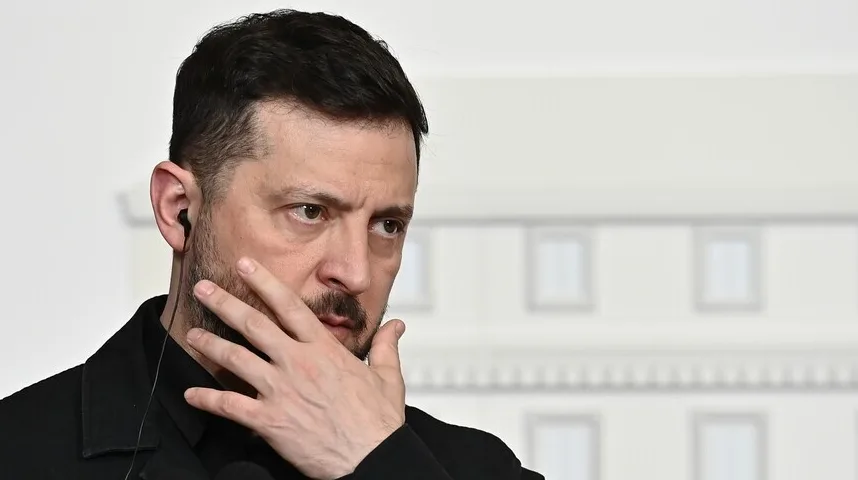 Volodimir Zelenski u crnom odijelu sa slušalicom u uhu, gleda u stranu