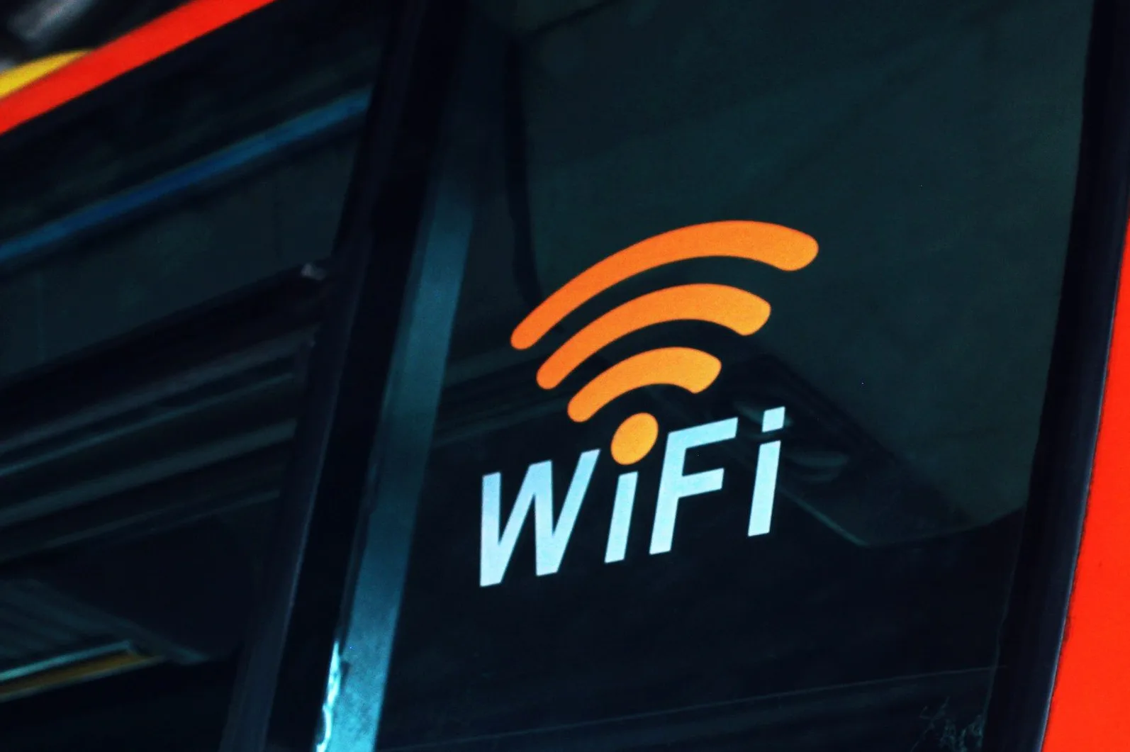 Naljepnica s WiFi simbolom i natpisom "WiFi" na tamnom staklu.