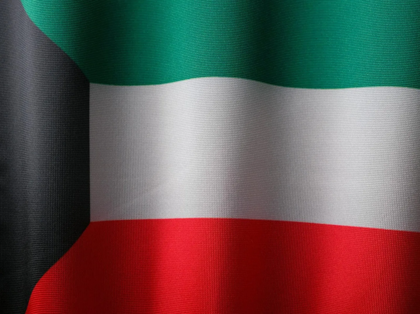 Detalj zastave Kuvajta, prikazuje horizontalne pruge zelene, bijele i crvene boje, sa crnim trouglom na lijevoj strani.