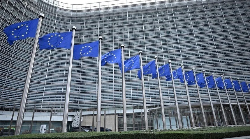 Više zastava Evropske unije vijori se ispred moderne, staklene zgrade Evropske komisije u Briselu.