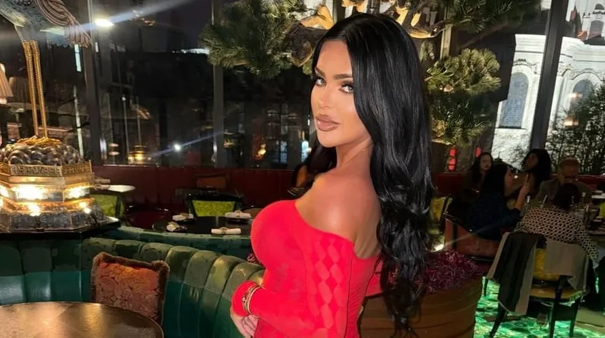 Žena u crvenoj haljini pozira u elegantnom restoranu