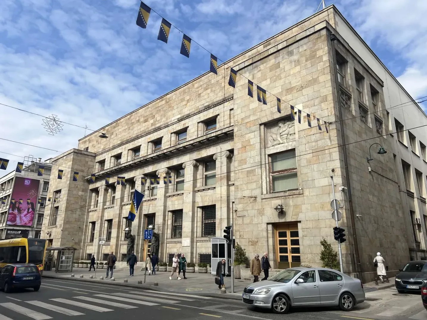 Fasada zgrade Centralne banke Bosne i Hercegovine u Sarajevu, sa istaknutim zastavicama Bosne i Hercegovine.