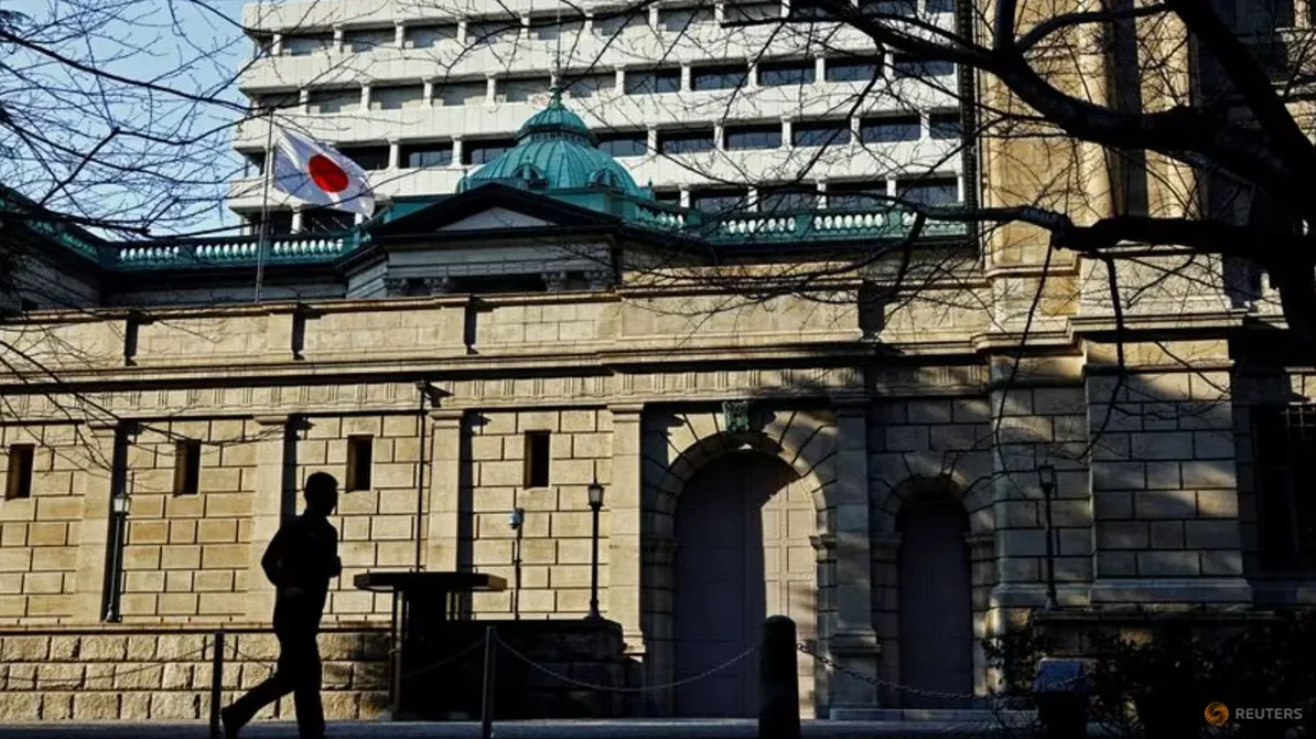 Silueta osobe koja prolazi pored istorijske zgrade Banke Japana pod zastavom Japana.