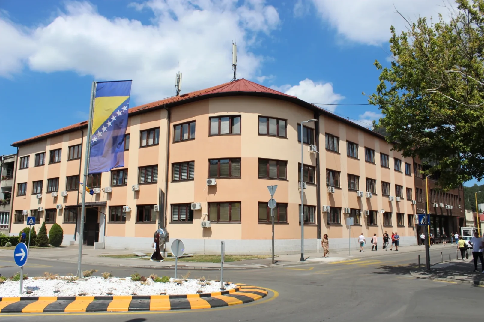 Pročelja zgrade sa zastavom Bosne i Hercegovine, ljudi na ulici.