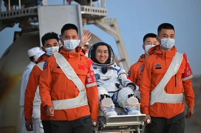 Kineski astronaut u svemirskom odijelu na nosilima koje nose članovi spasilačkog tima.