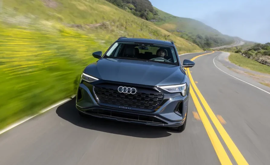 Sivi Audi e-tron vozi se zavojitom cestom kroz magloviti predio.
