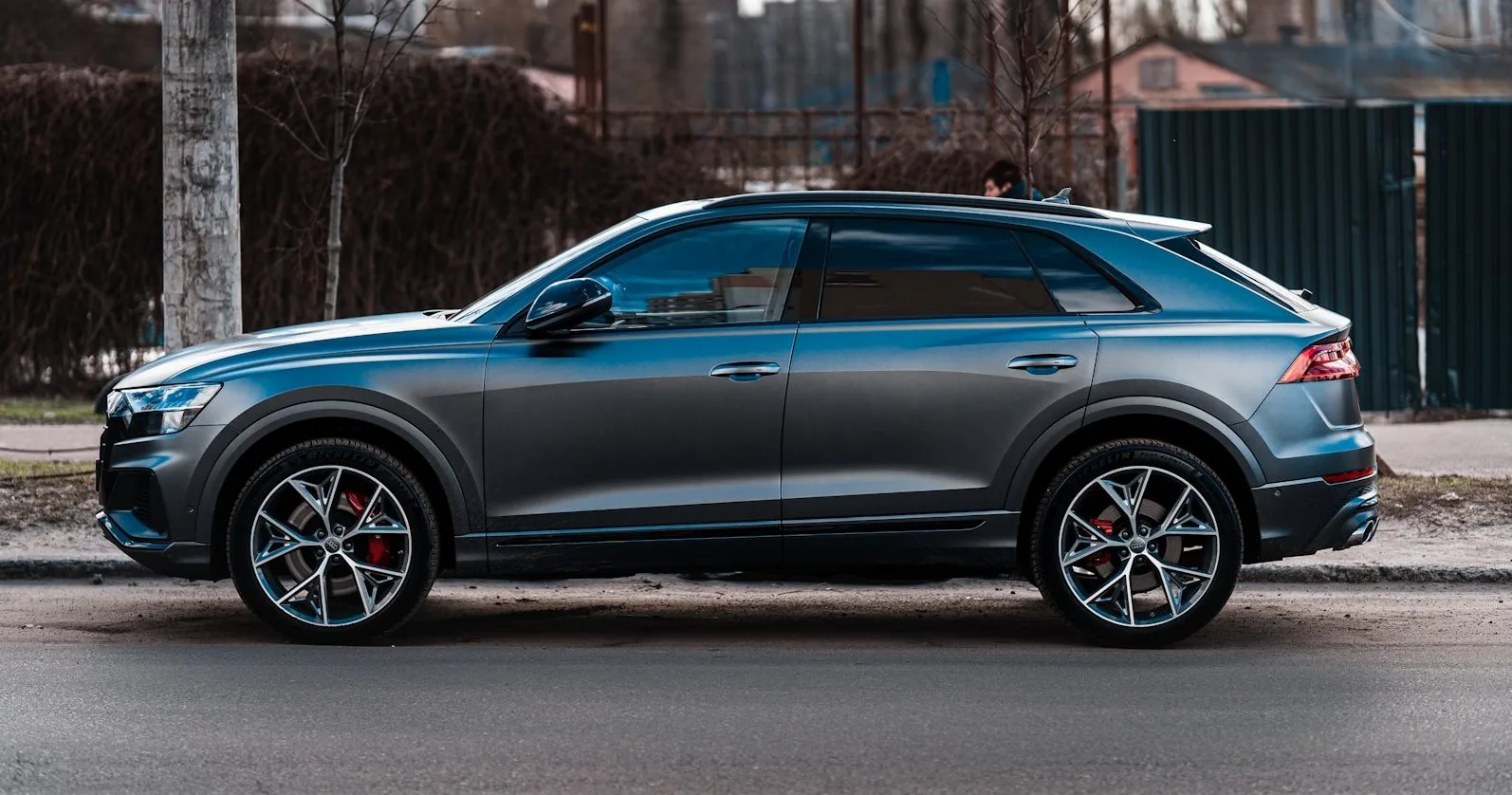 Tamnosivi Audi Q8 parkiran sa strane na asfaltiranoj ulici.