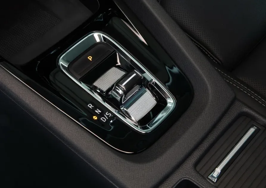 Detaljan pogled na centralnu konzolu modernog automobila, prikazujući automatski mjenjač sa osvijetljenim oznakama za parkiranje (P), vožnju unazad (R), neutralni položaj (N) i direktni pogon (D/S).