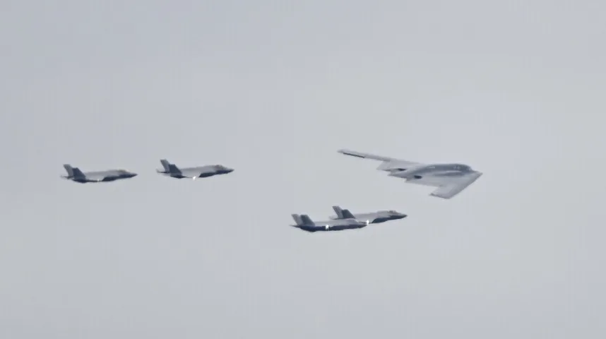 B-2 bombarder u pratnji više F-35 lovaca leti na nebu.
