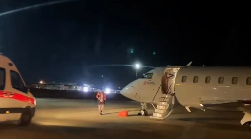 Hitna pomoć pored parkiranog aviona na aerodromu noću.