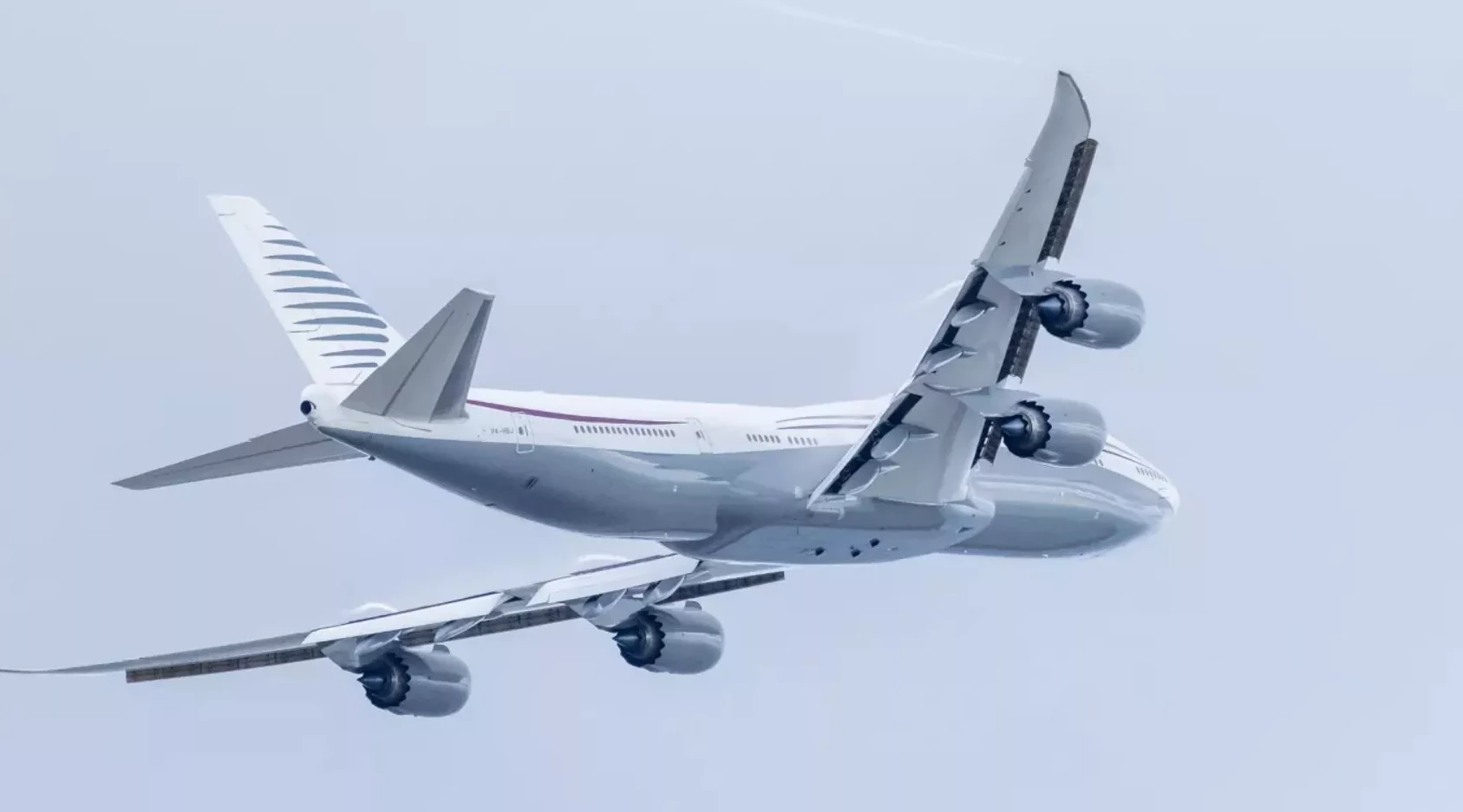 Bijeli avion sa četiri mlazna motora u letu, pogled odozdo