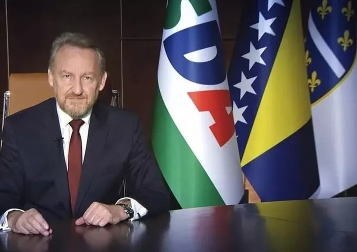 Bakir Izetbegović sjedi za stolom ispred zastava Stranke demokratske akcije (SDA) i Bosne i Hercegovine.