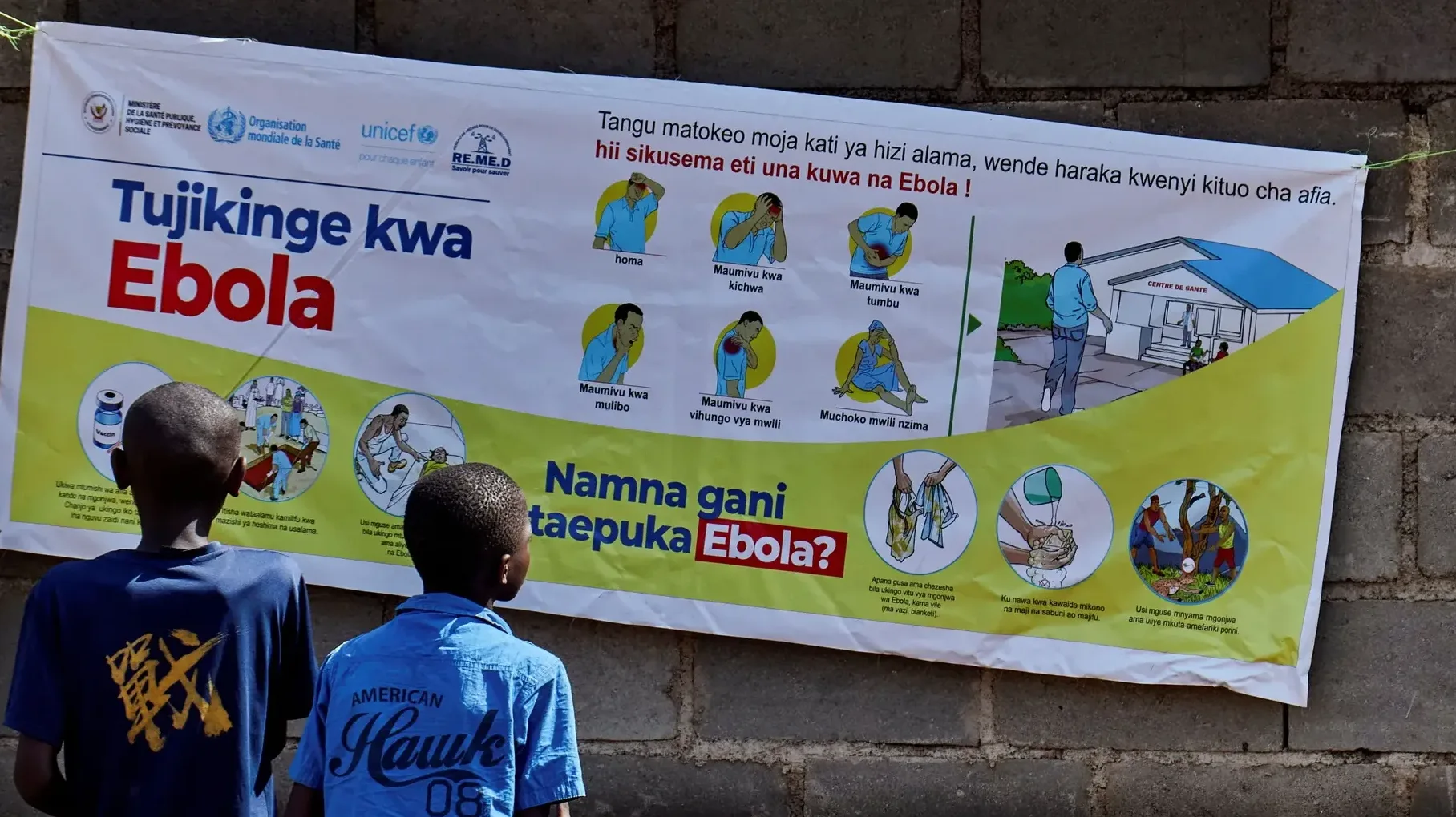 Baner sa informacijama o Eboli i njenom sprječavanju, postavljen na zidu. Na baneru su prikazani simptomi bolesti, kao i načini prevencije, uz logotipe Svjetske zdravstvene organizacije, UNICEF-a i drugih organizacija.