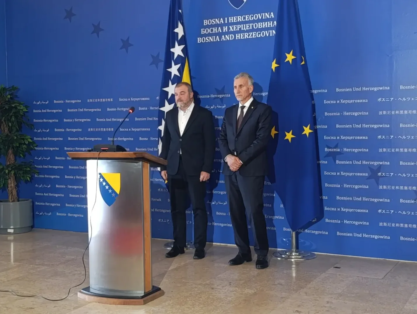 Dva gospodina u odijelima stoje ispred panoa sa logom Bosne i Hercegovine i Evropske unije.